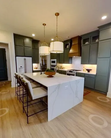 a room with stainless steel appliances kitchen island granite countertop a sink a stove and a wooden floors
