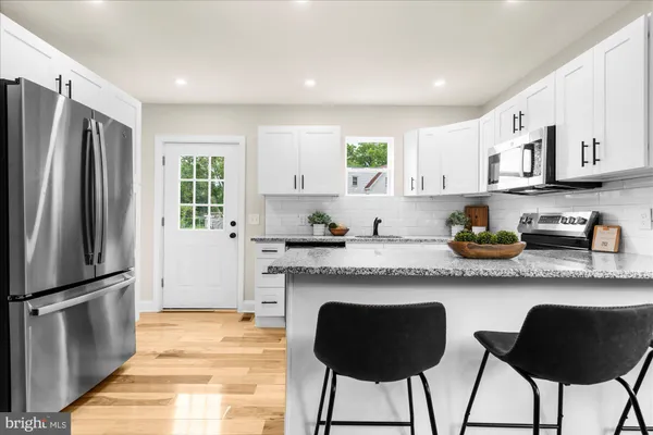 a kitchen with stainless steel appliances granite countertop a refrigerator a stove a sink and a refrigerator with wooden floor