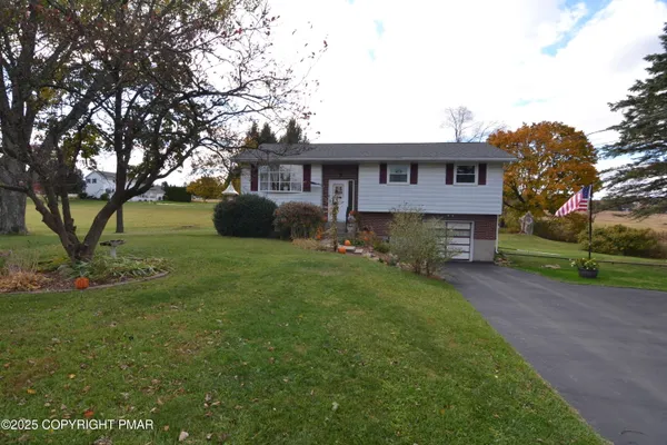 a view of a yard in front of a house with large tree