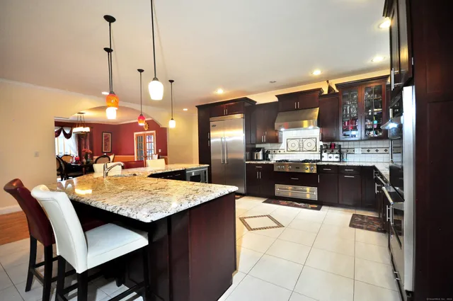a kitchen with stainless steel appliances kitchen island granite countertop a table chairs and a refrigerator