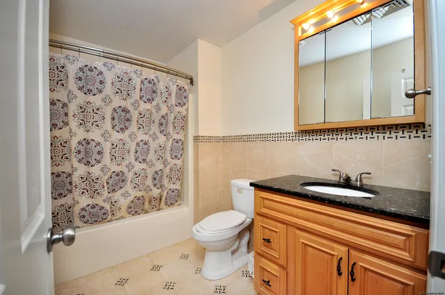 a bathroom with a granite countertop sink a toilet and a shower