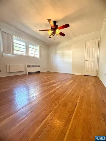 an empty room with wooden floor ceiling fan and windows
