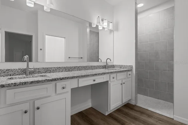 a bathroom with a granite countertop sink a mirror and a shower
