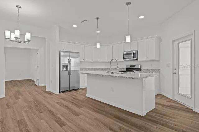 a kitchen with kitchen island white cabinets and stainless steel appliances