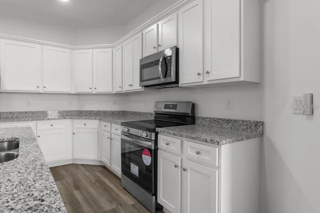 a kitchen with stainless steel appliances granite countertop a sink stove and cabinets