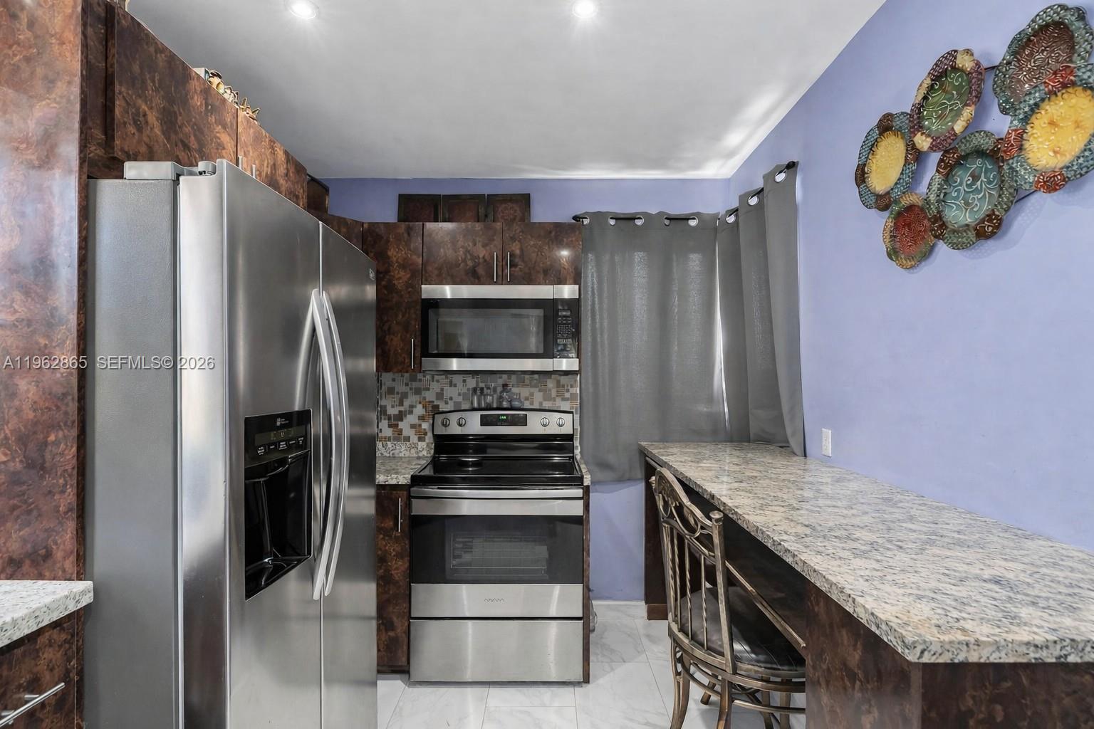 12201 Southwest 194th Terrace Miami, FL 33177 - Photo 8 of 34 a kitchen with stainless steel appliances granite countertop a refrigerator and a stove