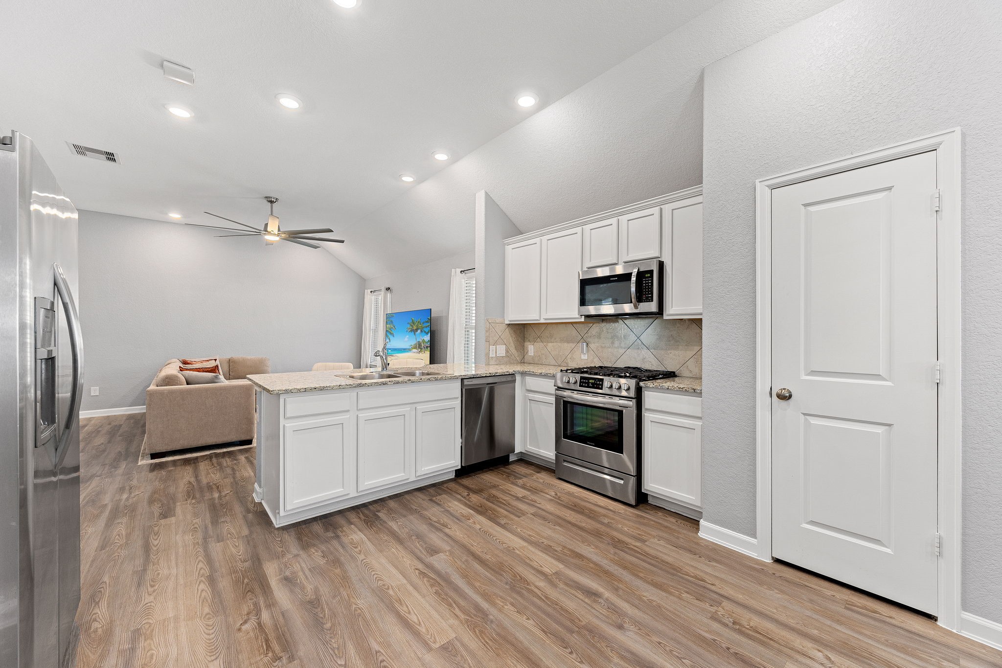 23002 Blackstone Park Road Katy, TX 77493 - Photo 11 of 36 a kitchen with granite countertop a refrigerator oven a sink dishwasher and white cabinets with wooden floor