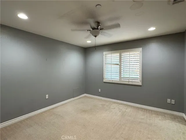 an empty room with a window and a fan