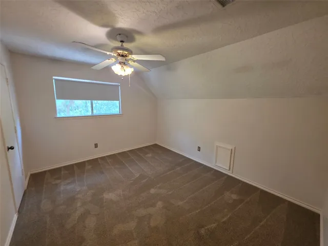 an empty room with a window and a chandelier fan