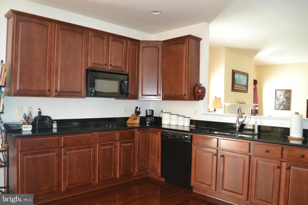 4145 Agency Loop Triangle, VA 22172 - Photo 7 of 24 a kitchen with granite countertop wooden cabinets and a sink
