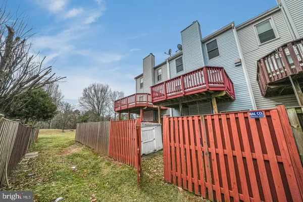 a view of a brick house with a small yard and deck