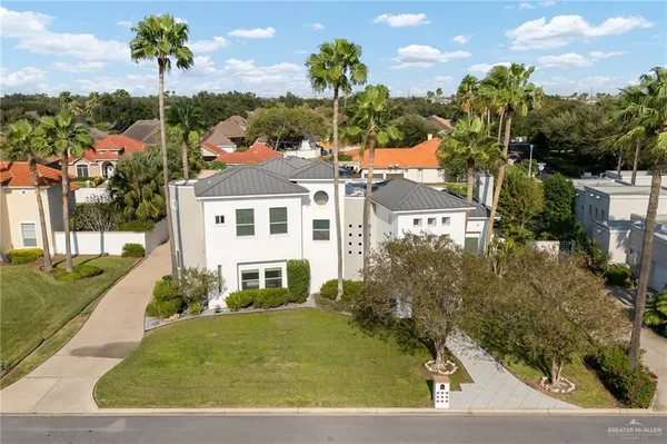 a view of a white house next to a yard with potted plants