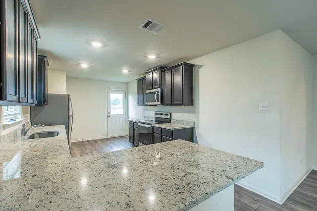 a kitchen with stainless steel appliances granite countertop a sink stove and refrigerator