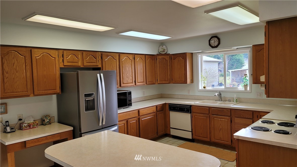 171 Mantle Road Sequim, WA 98382 - Photo 5 of 34 a kitchen with stainless steel appliances a sink a stove a refrigerator cabinets and a window