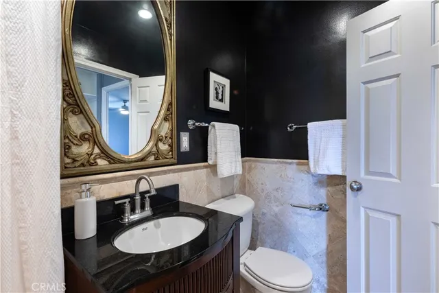 a bathroom with a granite countertop toilet sink and mirror