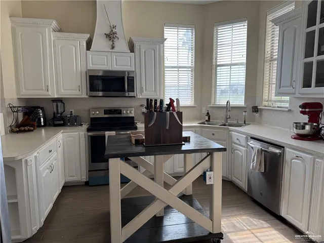 a kitchen with stainless steel appliances granite countertop a stove a sink and white cabinets