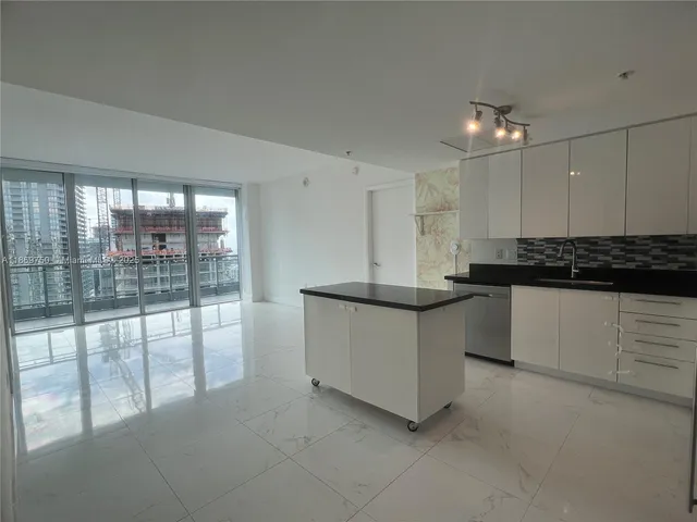 a large kitchen with kitchen island a large counter top space a stove and a large window