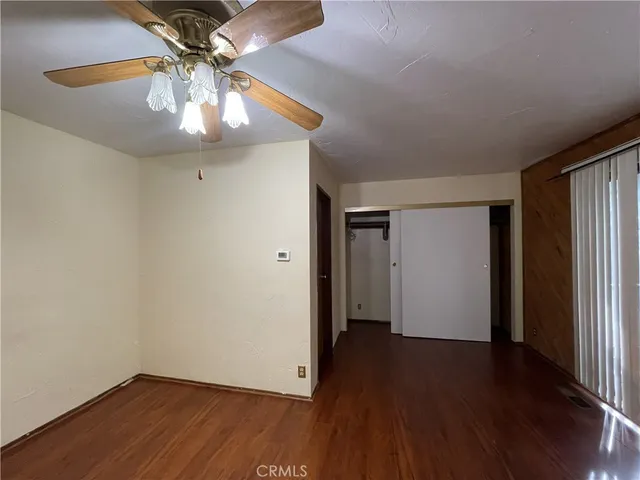 an empty room with wooden floor chandelier fan and closet area