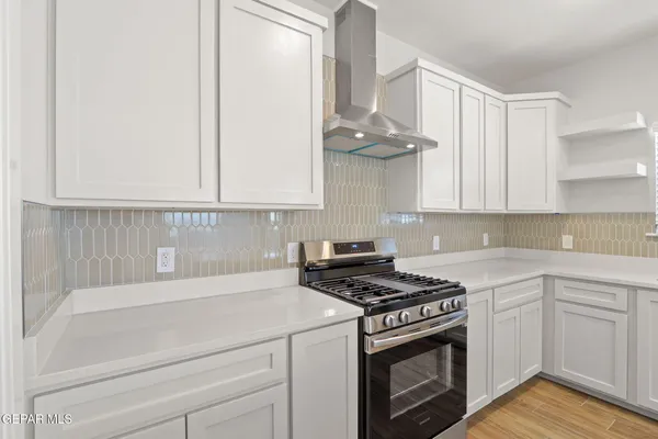a kitchen with stainless steel appliances white cabinets and a stove top oven