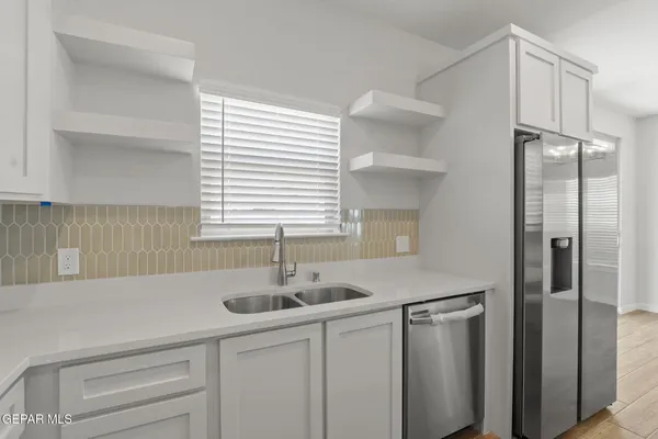 a kitchen with stainless steel appliances granite countertop a sink and a refrigerator
