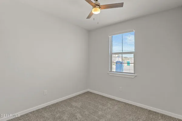 an empty room with a window and a fan