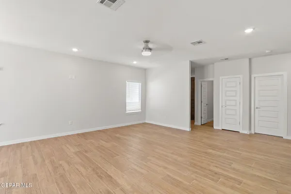 an empty room with wooden floor ceiling fan and windows