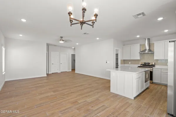 a large kitchen with kitchen island a stove a sink dishwasher and a refrigerator with wooden floor