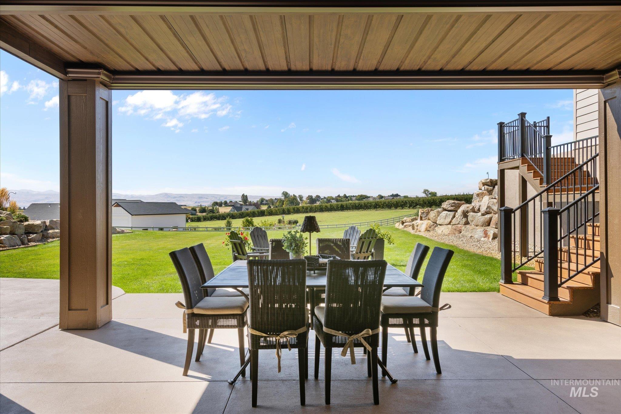 13683 Hockberger Ranch Road Caldwell, ID 83607 - Photo 32 of 50 Expansive covered patio with a textured ceiling and concrete flooring, featuring a multi-level deck with black railings and wood-finish steps