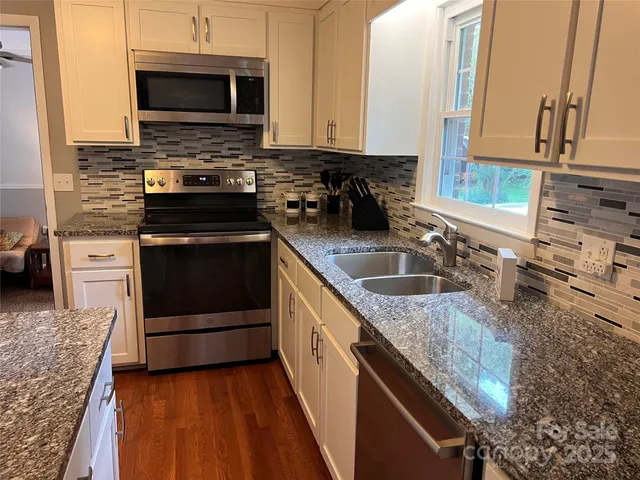 a kitchen with stainless steel appliances granite countertop a sink stove and microwave