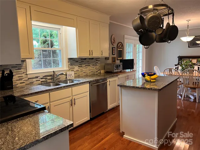 a kitchen with stainless steel appliances granite countertop a sink dishwasher a stove a dining table and chairs with wooden floor