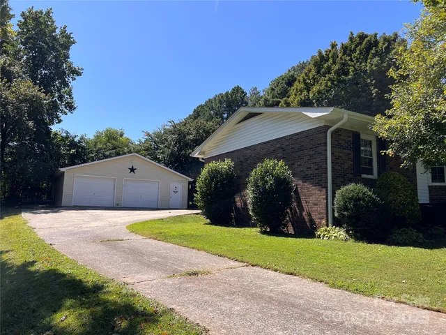 a view of a back yard with flower plants and a large tree