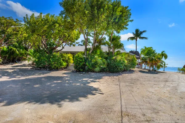 a living room with stainless steel appliances furniture a rug and a kitchen view