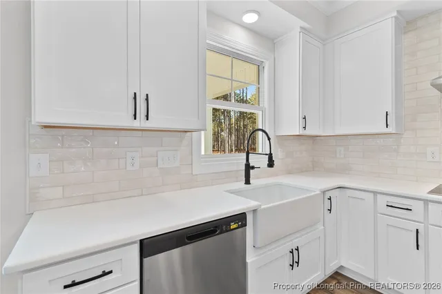 a kitchen with white cabinets a sink and dishwasher