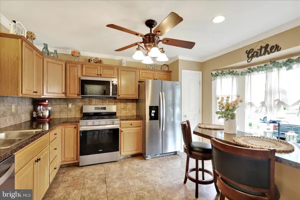 a kitchen with stainless steel appliances granite countertop a stove top oven a sink dishwasher a dining table and chairs with wooden floor