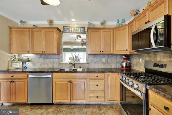 a kitchen with stainless steel appliances granite countertop a stove a sink and a microwave
