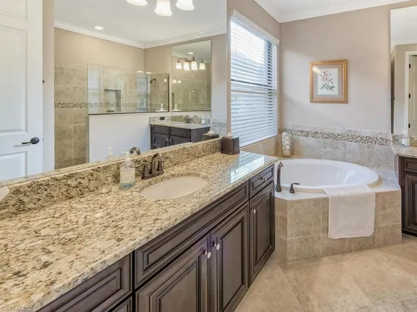 a bathroom with a granite countertop sink a bathtub and mirror