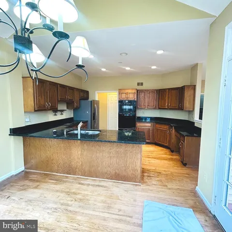 a large kitchen with stainless steel appliances granite countertop a granite counter tops and a view of living room