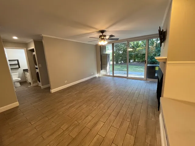a view of empty room with wooden floor and fan