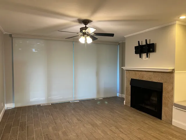 a view of a livingroom with a fireplace a ceiling fan and wooden floor