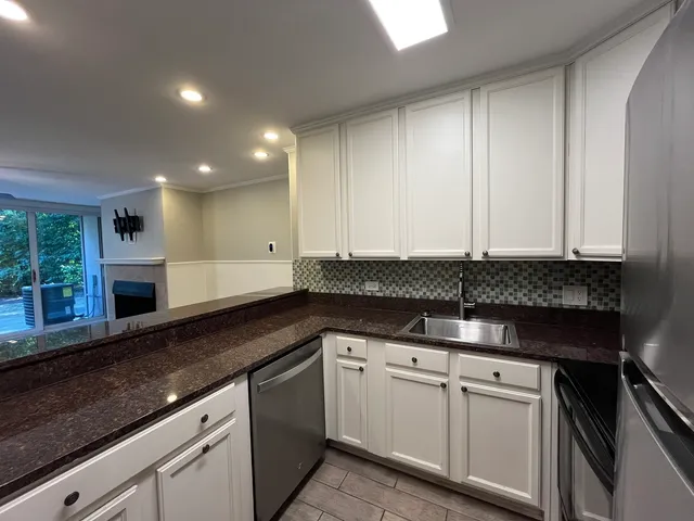 a kitchen with granite countertop white cabinets and white appliances