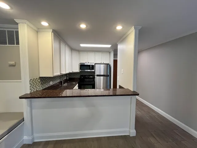 a view of a kitchen with stainless steel appliances granite countertop a stove and a refrigerator