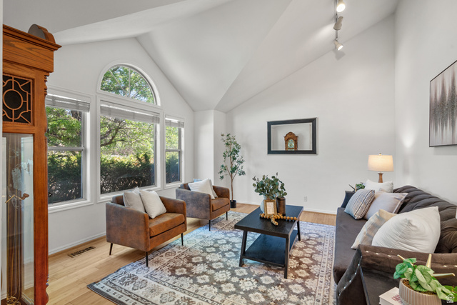 1726 Wasatch Boulevard Sandy, UT 84092 - Photo 2 of 38 Vaulted ceiling living area featuring light wood-finish flooring, a wall of windows including an arched transom