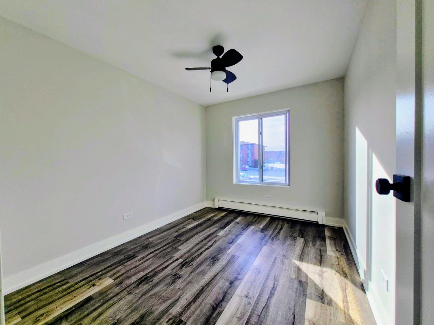239 North Gregory Street, Unit 8 Aurora, IL 60504 - Photo 3 of 15 an empty room with wooden floor a ceiling fan and windows