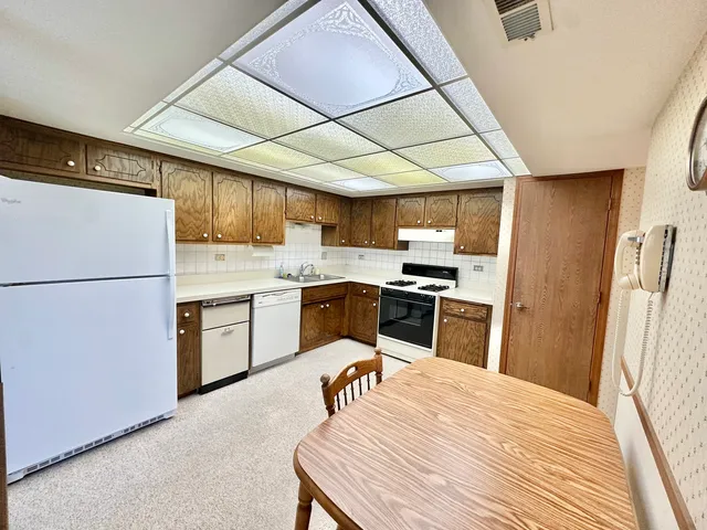 a kitchen with granite countertop a refrigerator a sink dishwasher a stove a microwave oven with a dining table and chairs