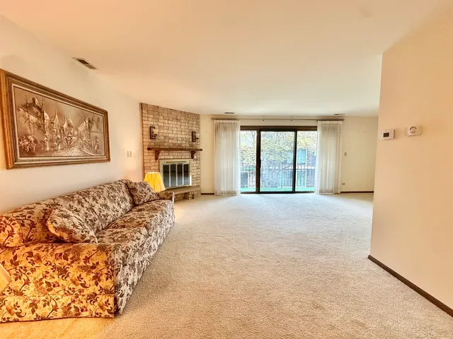 a view of a livingroom with furniture a fireplace and large windows