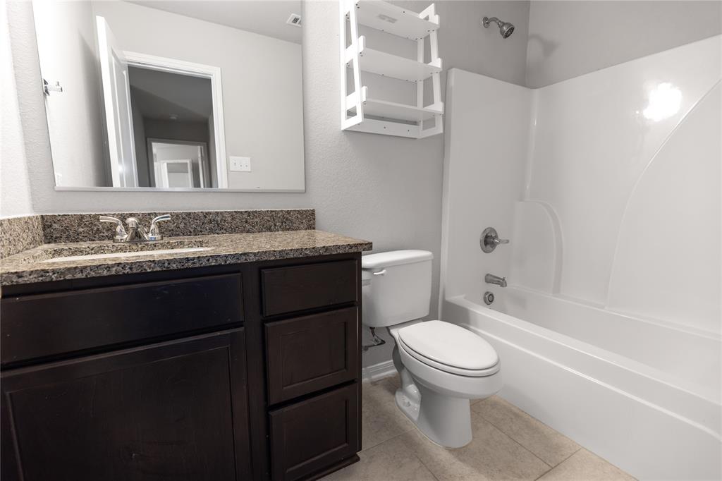 3933 Rimfire Road Waco, TX 76705 - Photo 14 of 27 a bathroom with a granite countertop toilet sink and mirror