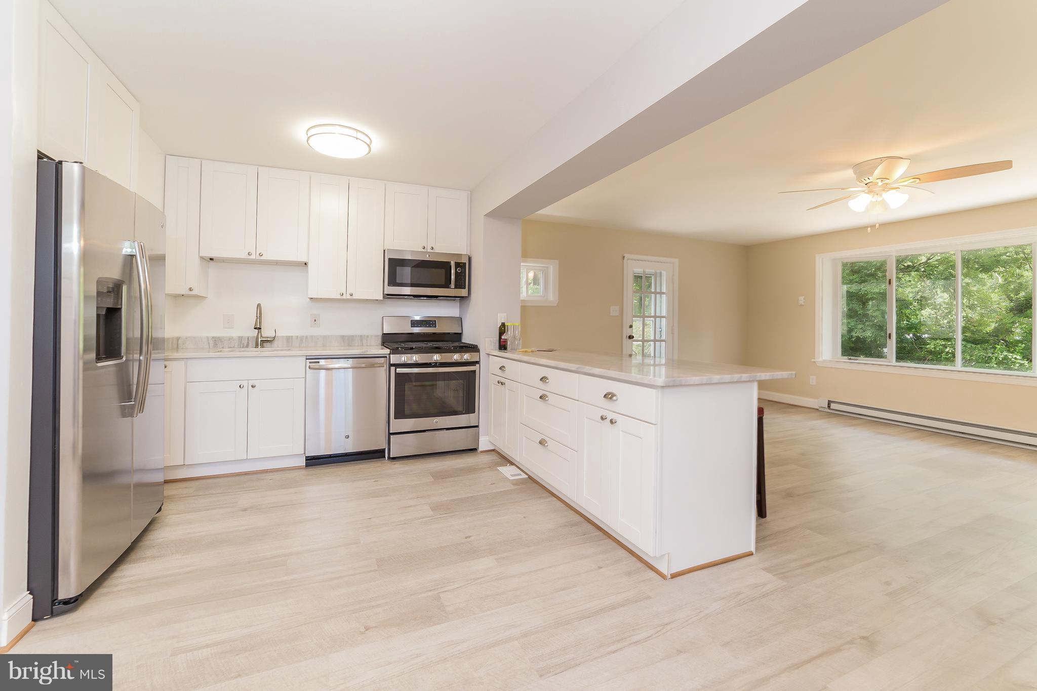917 Benson Terrace Silver Spring, MD 20901 - Photo 6 of 25 a large kitchen with stainless steel appliances granite countertop a stove a sink dishwasher a refrigerator and white cabinets with wooden floor