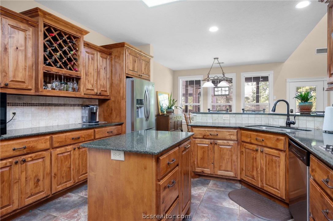 6400 Koppe Bridge Road College Station, TX 77845 - Photo 21 of 47 Kitchen featuring custom wood finish cabinetry, dark granite counters, decorative backsplash, stainless steel appliances, and pendant lighting.