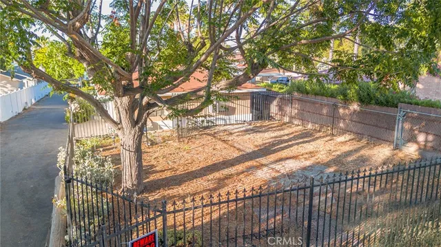a view of backyard with wooden fence and large trees
