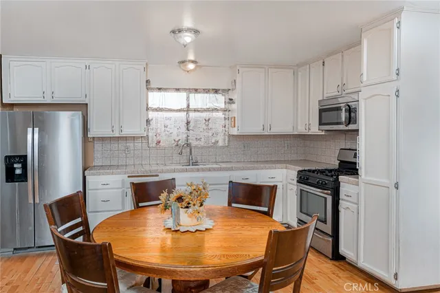 a kitchen with stainless steel appliances granite countertop a stove a refrigerator a sink a dining table and chairs